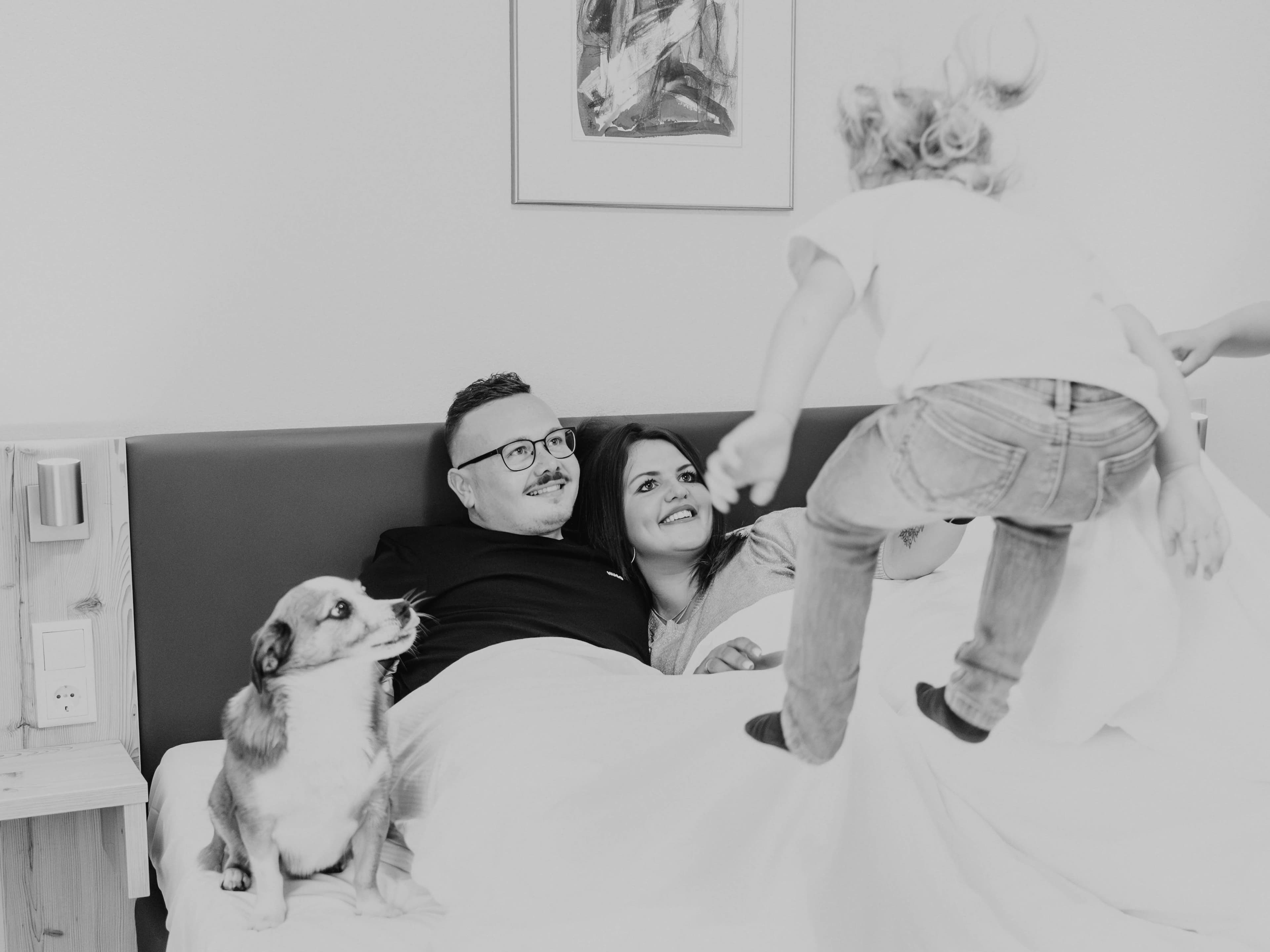 Familie mit Kind und Hund auf dem Bett im Sonnenhotel Bayerischer Hof